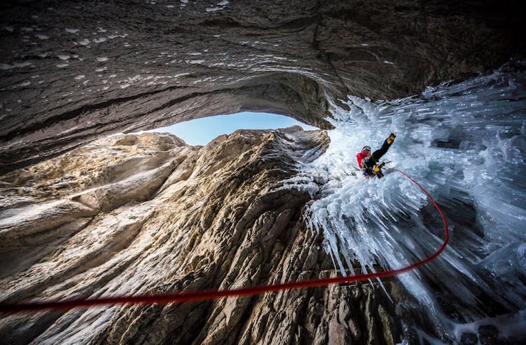 An alpine climber navigates ice sheets within a rocky crag