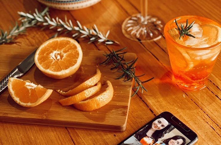 An Aperol Spritz sits next to orange slices and a phone. 