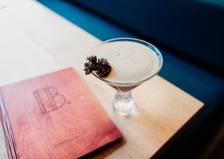 an espresso martini beside a menu engraved with a B