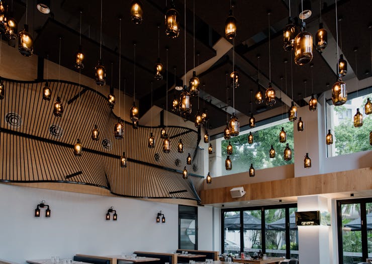 beer bottle lamps hanging from the ceiling of a brewpub