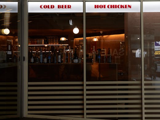 The shop front of Belles Chicken with a light sign that reads 'Cold Beer' and 'Hot Chicken'. 