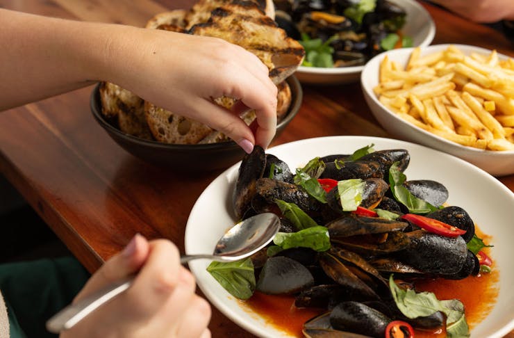 A table full with bottomless mussels. chips, bread and drinks