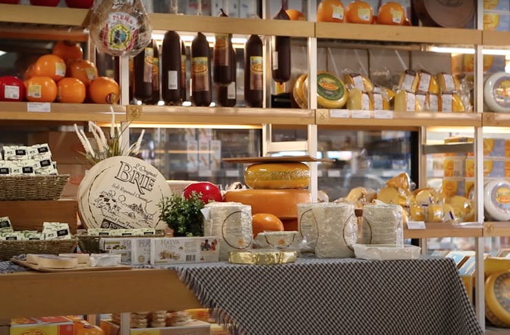 A room full of different kinds of cheese stacked on wooden shelves