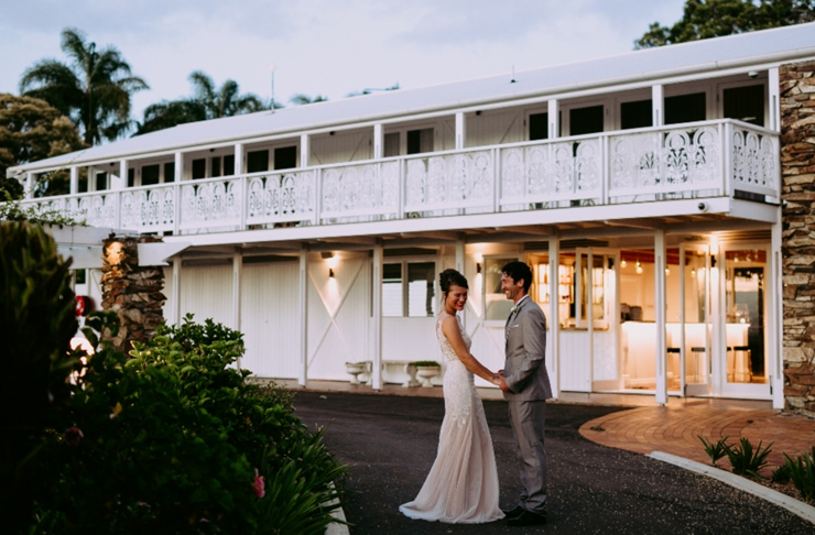 A bride and groom embrace outside of a white plantation style house at Fins in Duranbah.