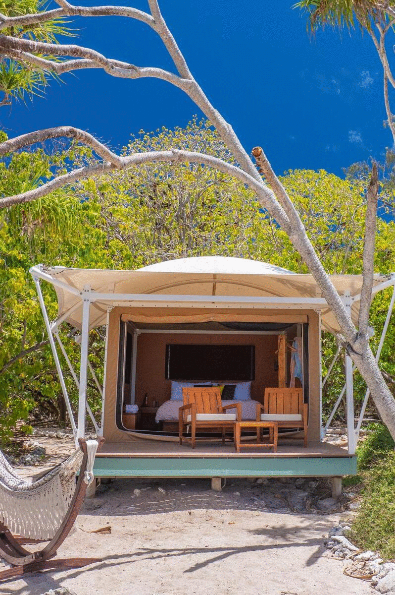 An ecolodge hides behind palm fronds on the beach.