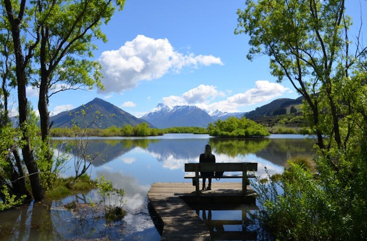 Someone sits on a peaceful bench looking out over a beautiful vista in Glenorchy.