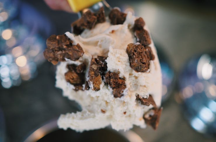 Close up of a scoop of butterfinger gelato on the ice cream scooper