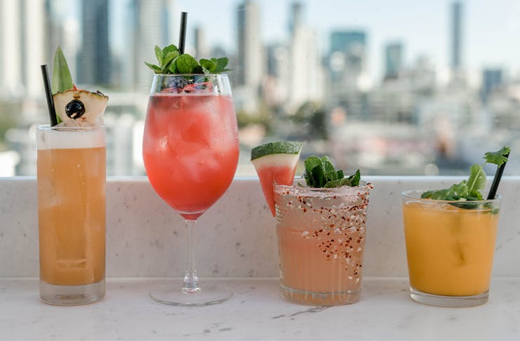 4 cocktails in a row on a bench overlooking the city.