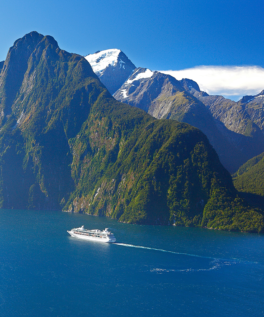 A boat travels down the pass at Milford Sound with stunning scenery.