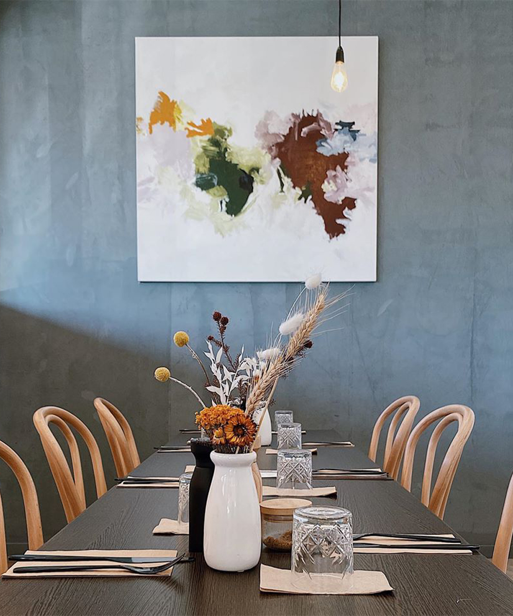 A long table with a painting on the wall visible at the end.