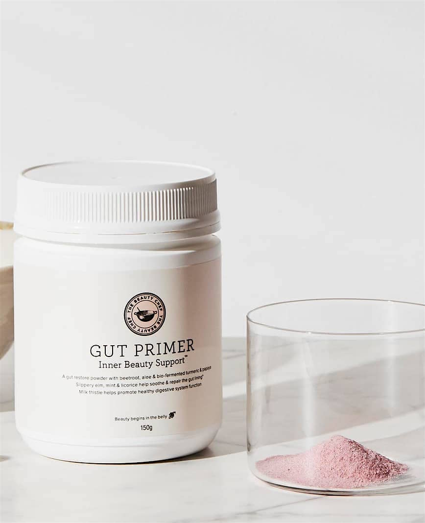 A clear jar filled with pink powder sits on a table next to a plastic tub labelled The Beauty Chef Gut Primer Inner Beauty Support.