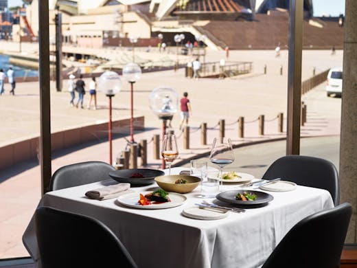 A table set with a white table cloth at Aria in Sydney, with the Opera House in the background