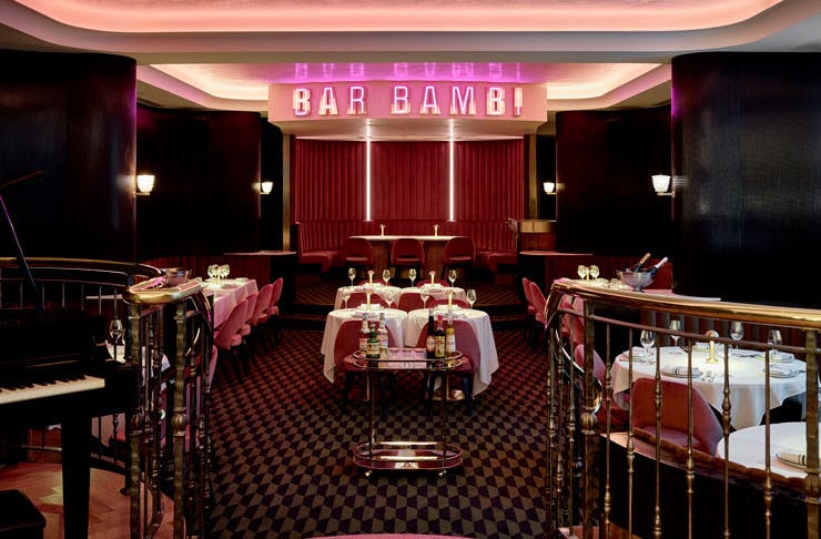 The dining room at Bar Bambi, with cherry red carpet, pink velvet chairs and a pink neon sign that reads 