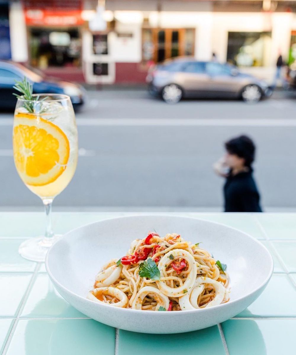 a bowl of pasta and a drink looking onto the street