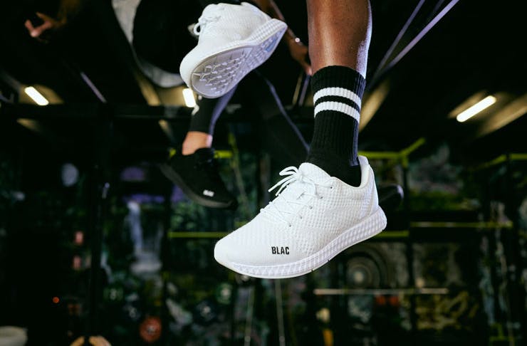 Feet wearing bright white sneakers and black socks with two white stripes. 