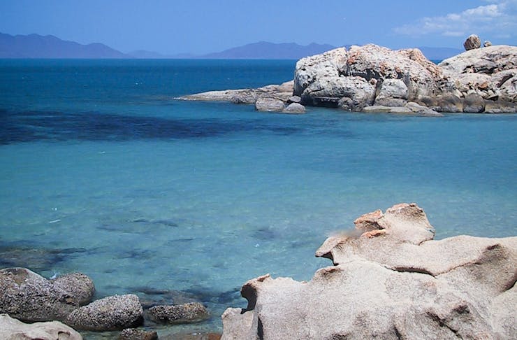 a blue bay with boulders in it 
