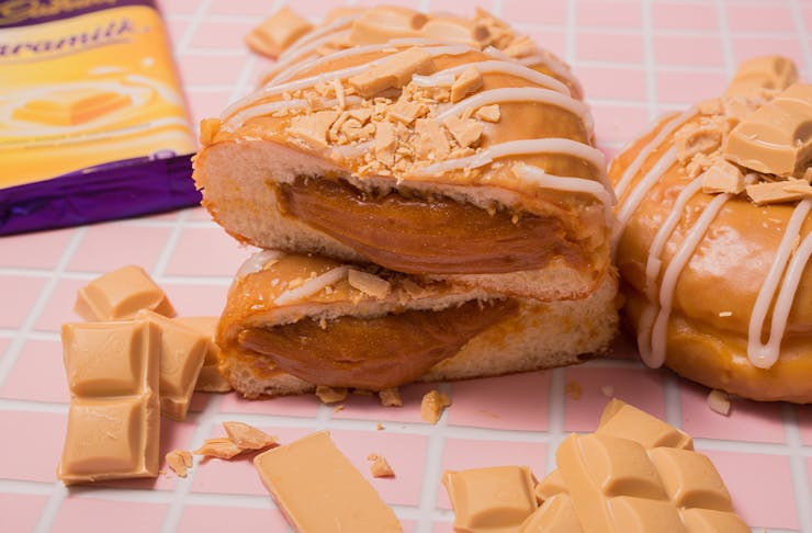 a doughnut filled with caramel, cut in half and stacked, caramilk chocolate scattered around
