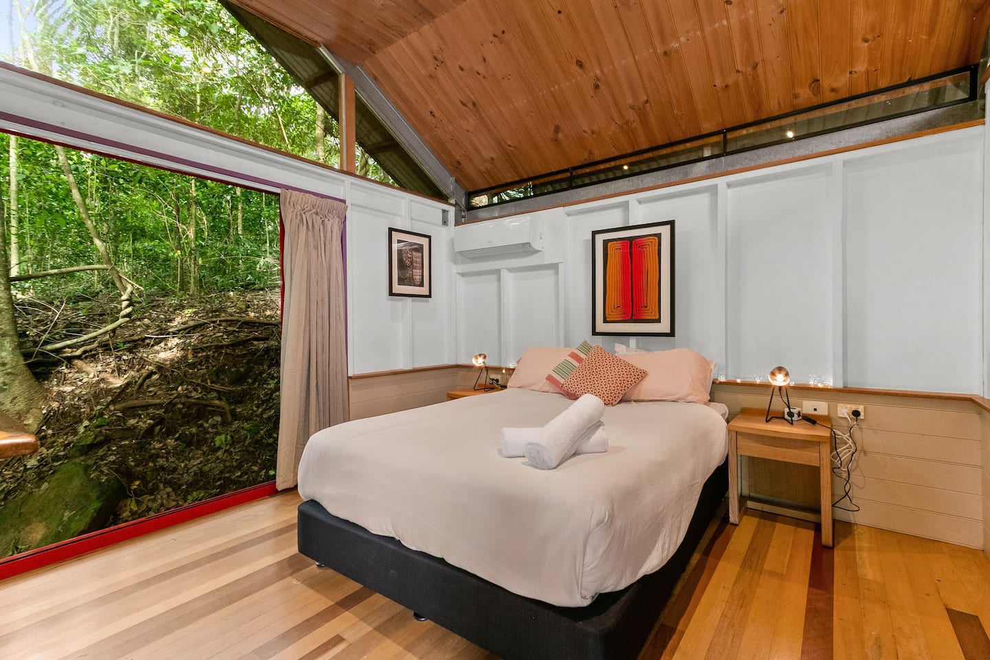 a bedroom with a large window looking out at a forest