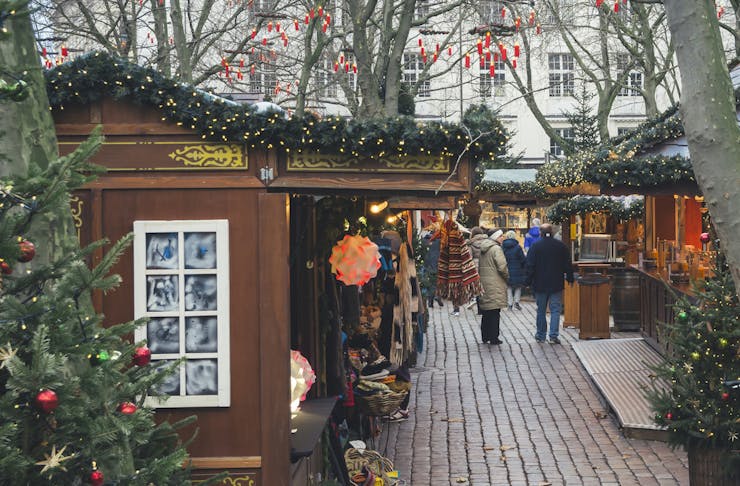 A European style Christmas market with stalls topped with lights.