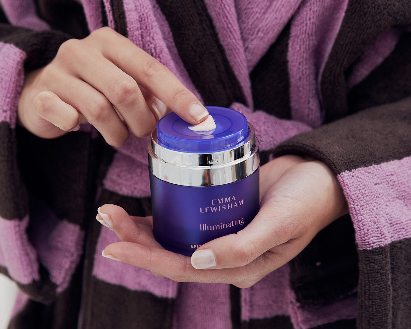 The Brighten your day creme is held in someone's hands.