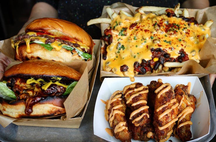 A spread of takeaway food from Dirty Moes, featuring burgers, chilli cheese fries and chicken wings. 