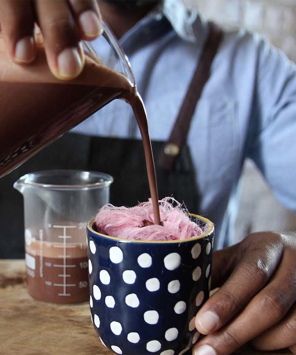 A man pours a decadent fairy floss hot chocolate at Elisabeth, one of Auckland's best hot chocolate shops.