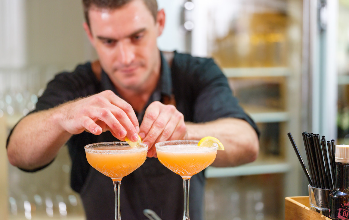 a bartender garnishes two orange cocktails at a bar in Esperance