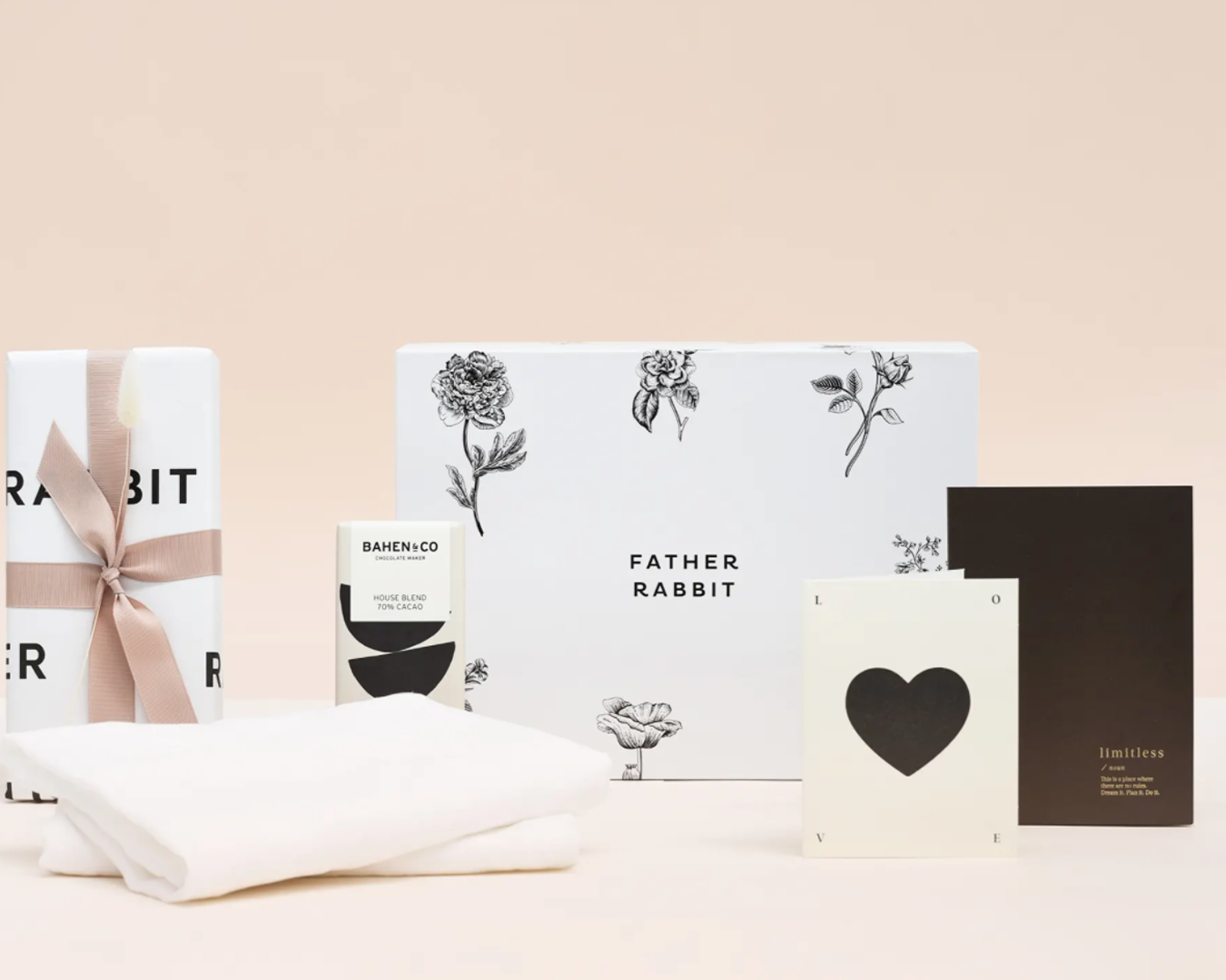 An array of black and white gifts like pillow cases and chocolate sitting beside a black and white illustrated gift box