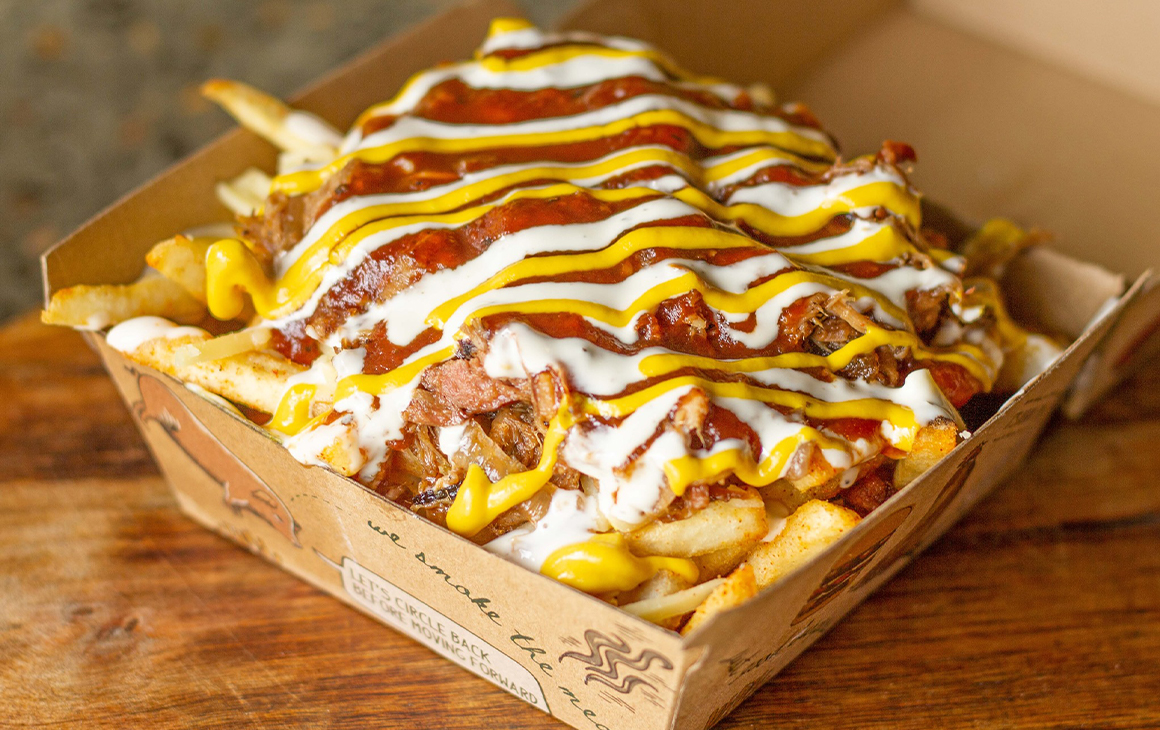 a container of fries topped with pulled meats, sauce and cheese