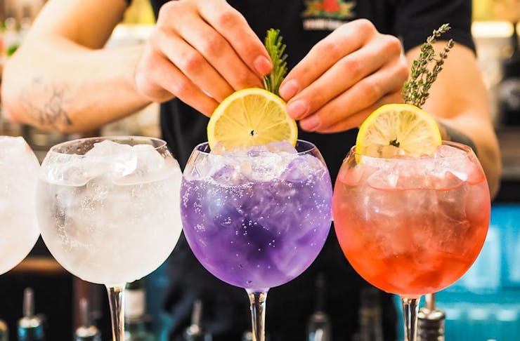 colourful gin and tonics in goblet glasses lined up on a bar