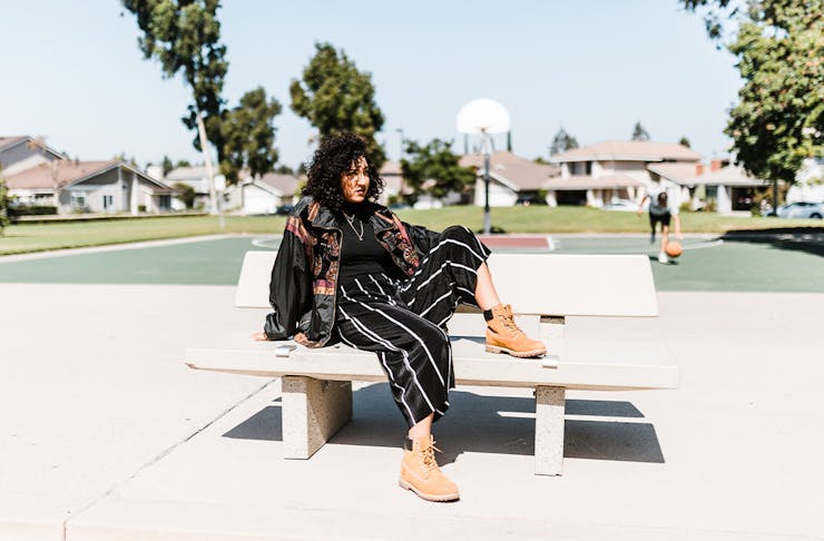 a woman sitting on a park bench by a basketball court