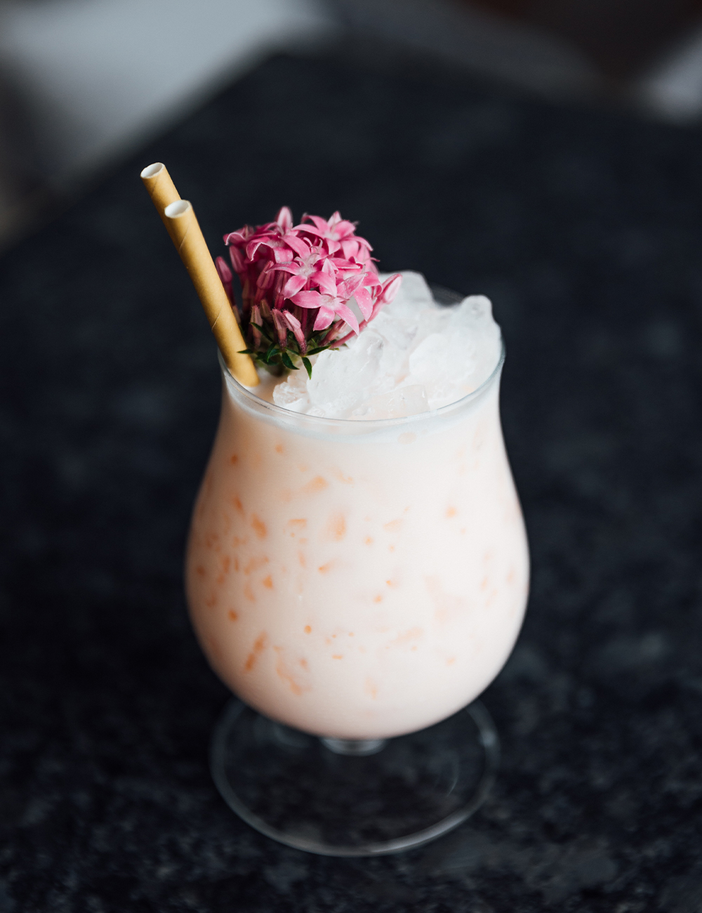a pink pina colada topped with flowers