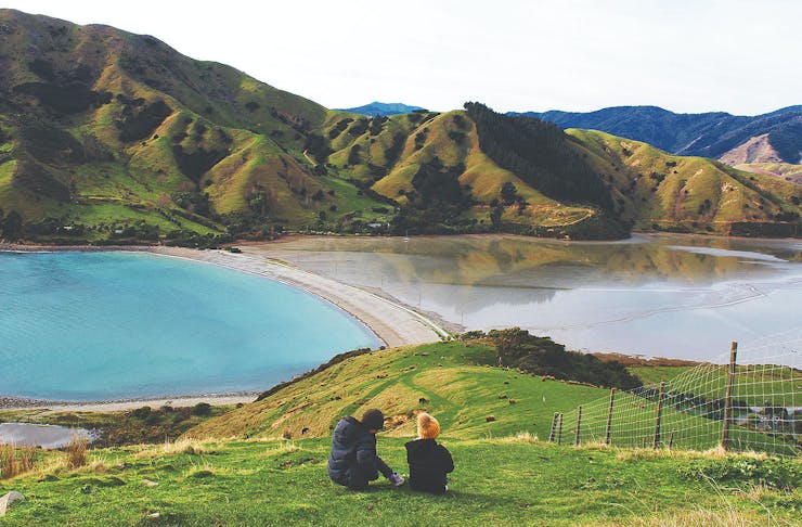 A couple sit on a hill in Nelson.