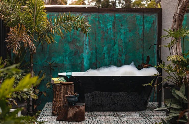 a bath in a courtyard in front of a green wall
