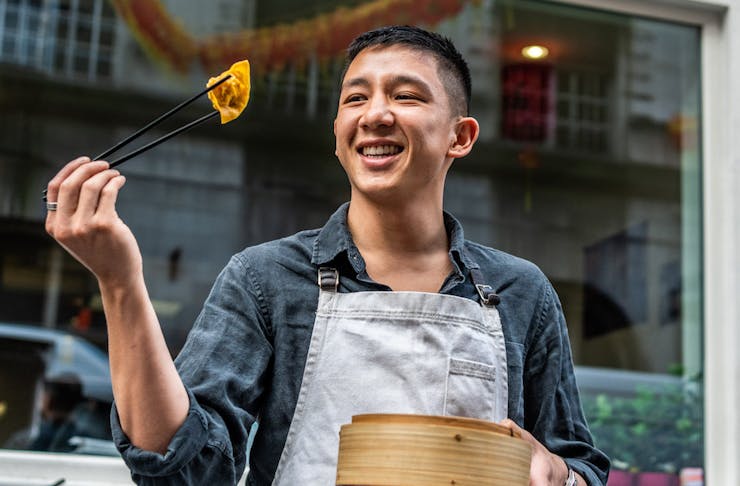 Brendan Pang holds up dumpling with chopsticks