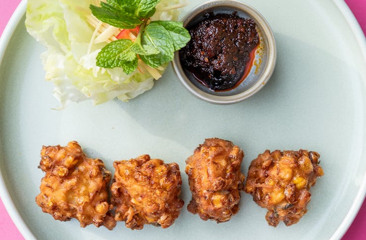 a plate of corn fritters with lettuce and sauce