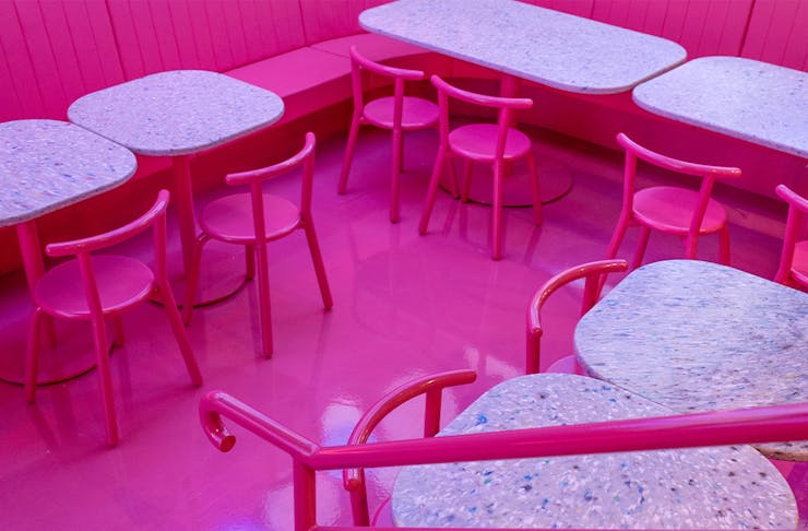 a restaurant interior with pink floors and chairs