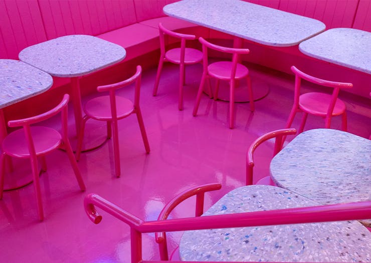 a restaurant interior with pink floors and chairs