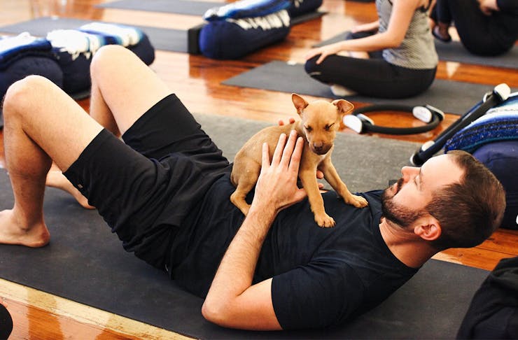 a man on a yoga mat holding a puppy