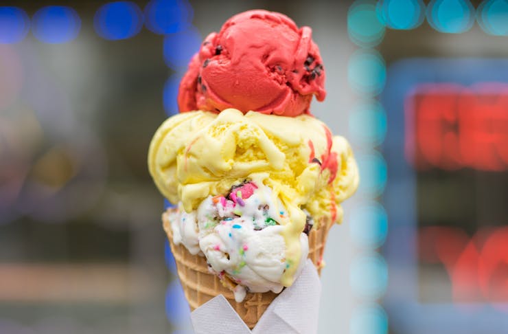 three scoops of ice cream stacked on a waffle cone