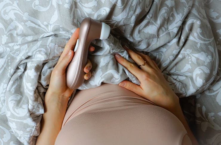 a woman in bed holding a vibrator