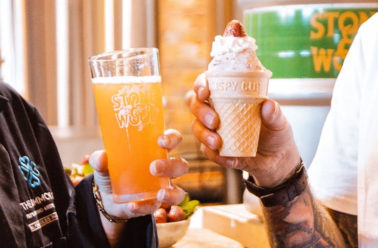 A beer pint and a strawberry ice cream being held by two people