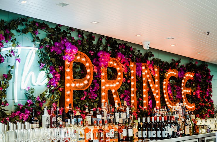 flower wall with 'prince' in neons behind a bar