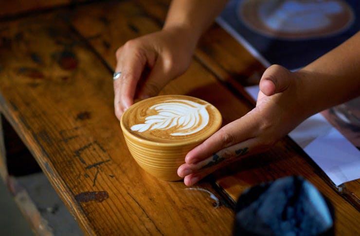A latte being presented on a wooden table. 