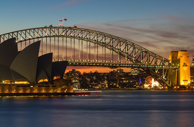 a nighttime shot of the sydney harbour bridge and opera house