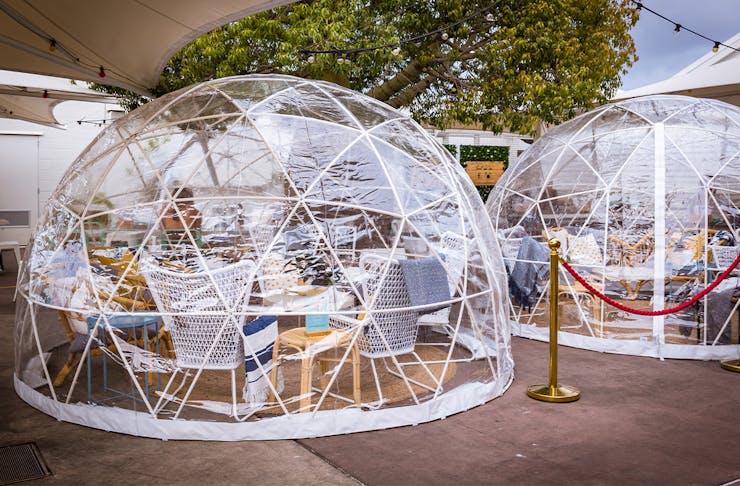 Two clear igloos with tables inside 
