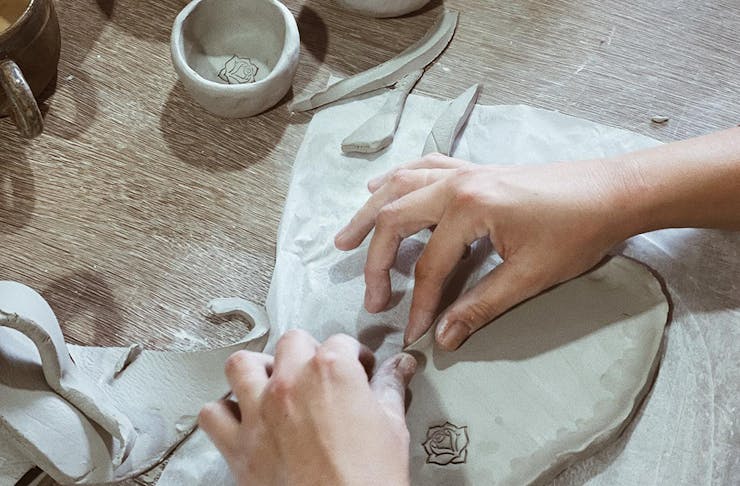 hands moulding clay into a plate