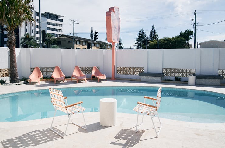 white and pink chairs sit around a blue pool