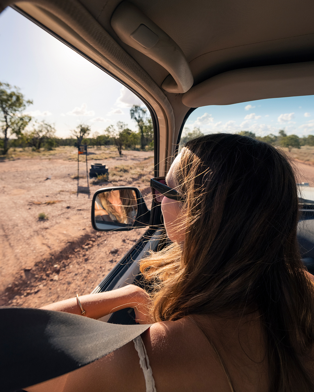 woman leaning on car window looking, driving through the outback