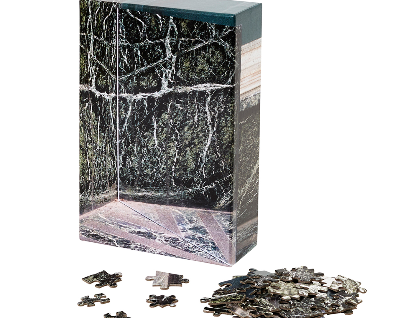 Puzzle box featuring grey, marble pattern. In front of it are a few single puzzle pieces.